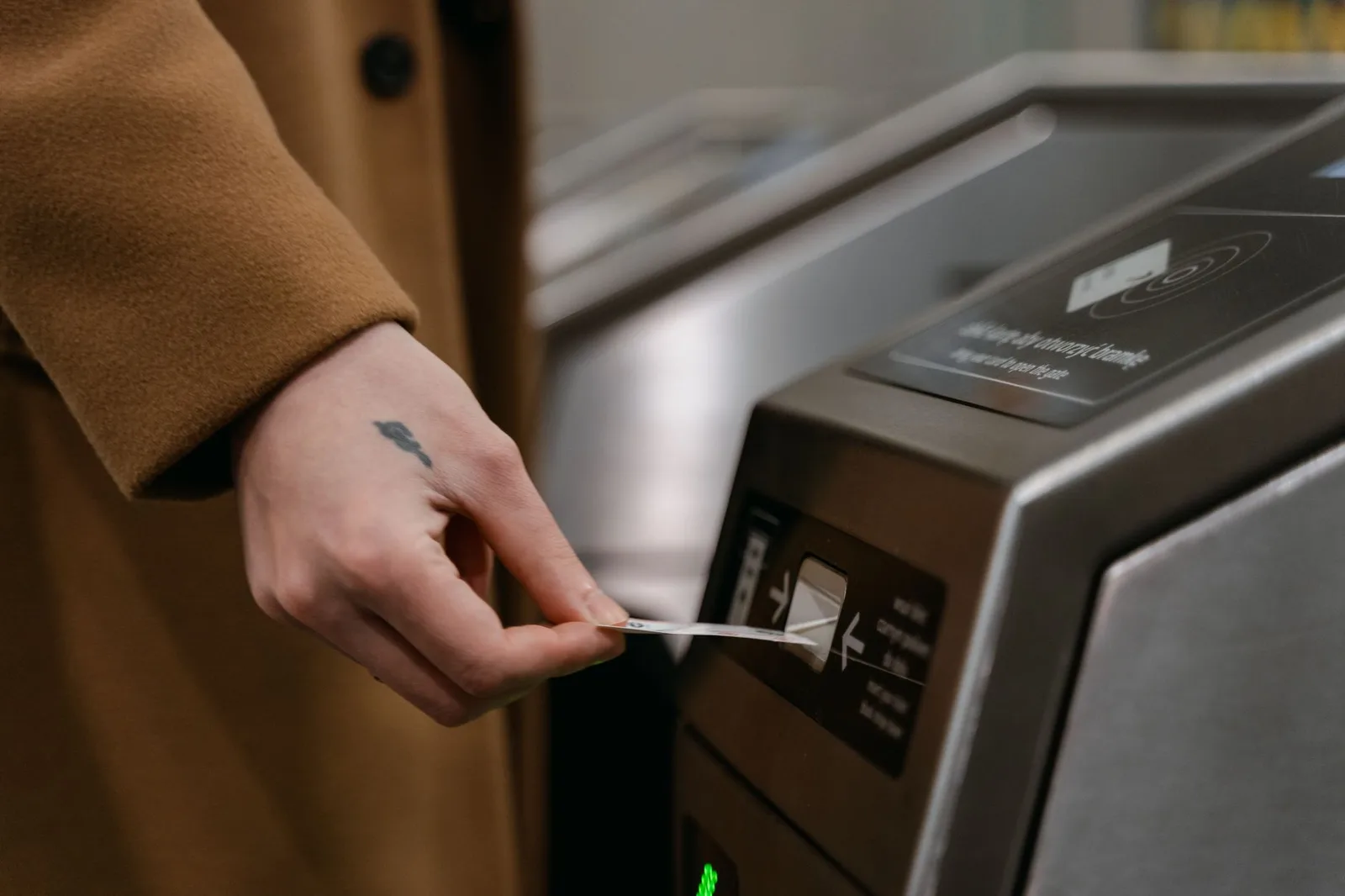 יד מצמידה כרטיס סואיקה לקורא בשער כניסה לרכבת בתחנה עמוסה ביפן